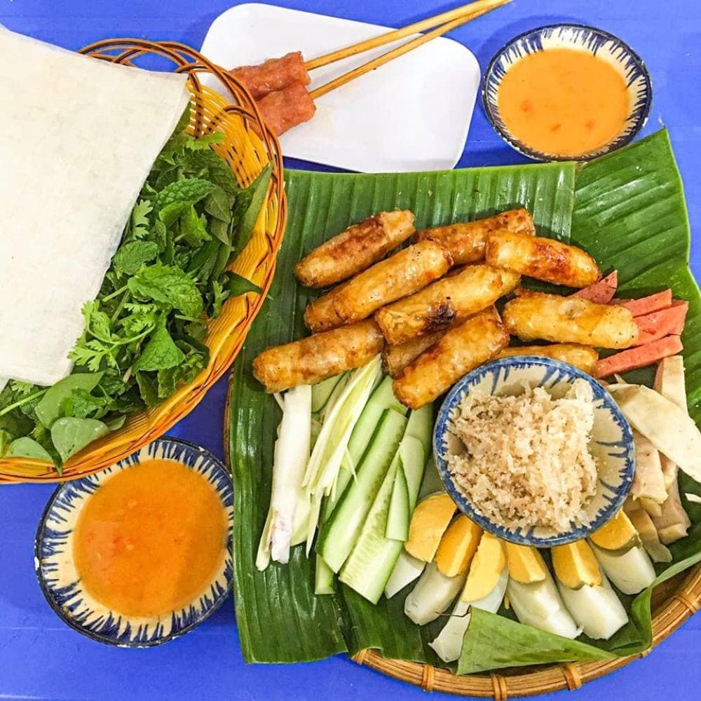 Chả giò cá trích ăn kèm dưa leo, rau sống và chấm mắm đậu phộng béo ngậy